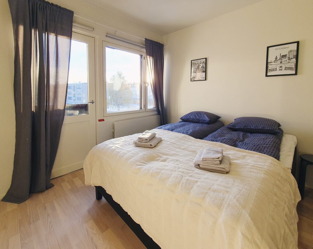 Ilta-aurinko paistaa siistin yksiön ikkunasta. Huoneessa on leveä parisänky, ja ikkunasta näkyy Rovaniemen keskusta.