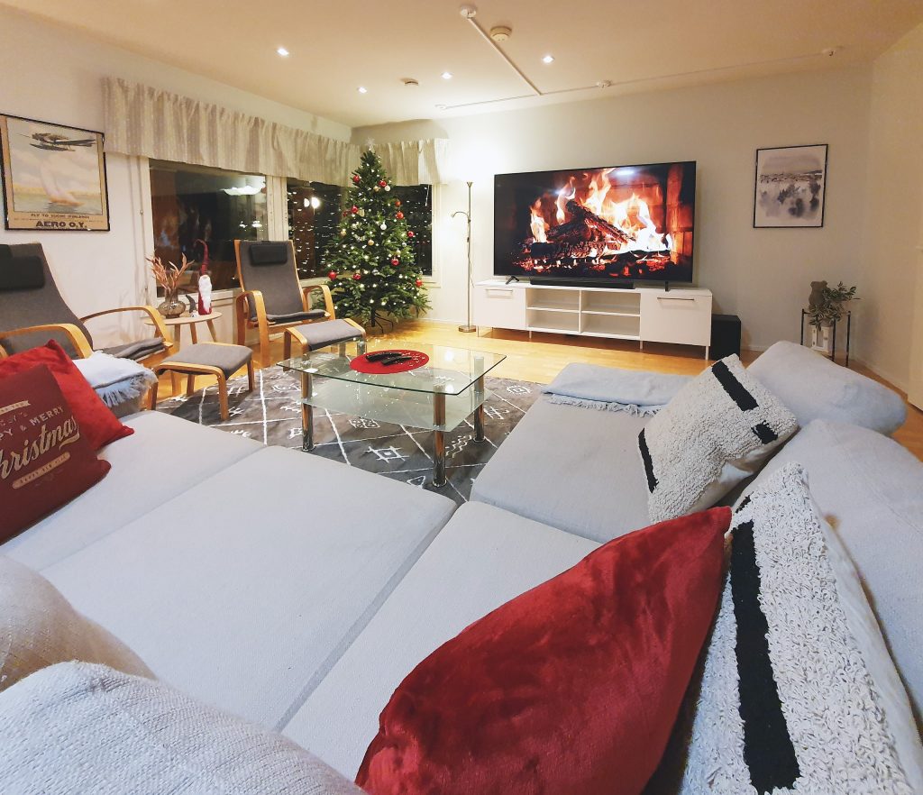 Paritalon tilava olohuone on somistettu jouluisaksi ja suuressa televisiossa on video takkatulesta.