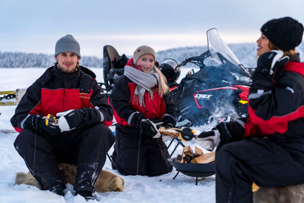 Turistit pilkkimässä jäällä moottorikelkkasafarilla.